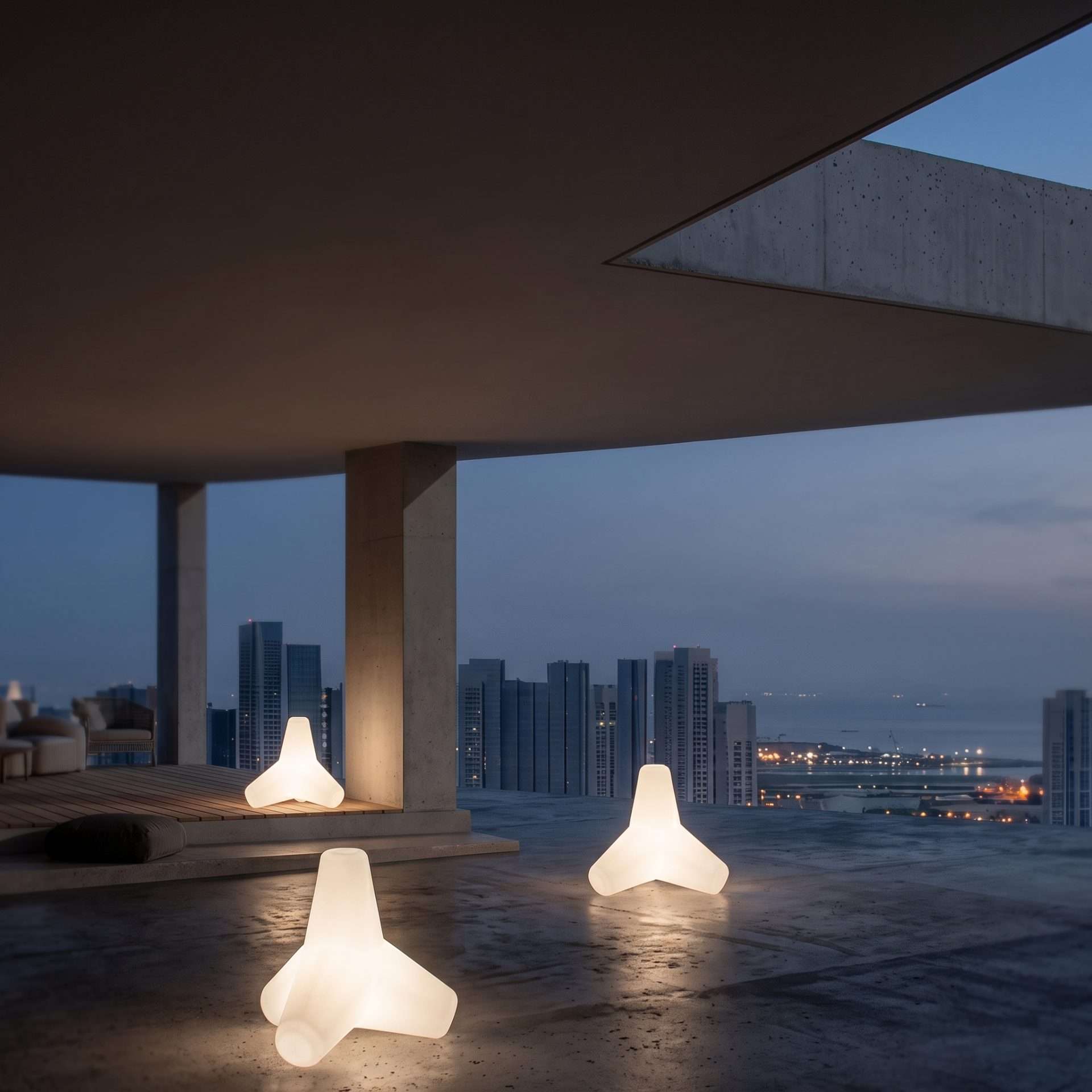Lampade da esterno Frangiflutti accese su una terrazza in cemento, con lo skyline sul mare al tramonto
